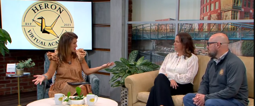 Un entrevistador sentado en una silla y entrevistando a dos personas que están sentadas en un sofá.